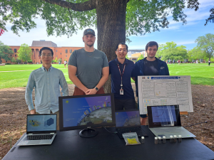 Group of people standing at table with their research on display.