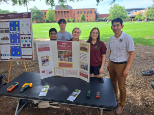 Group of people standing at table with their research on display.