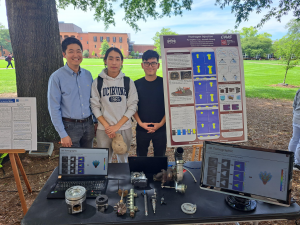 Group of people standing at table with their research on display.