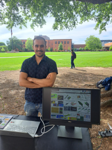 A person standing at table with their research on display.