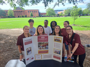 Group of people standing at table with their research on display.