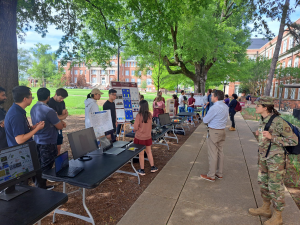 Groups of people are set up at tables with displays of their research.